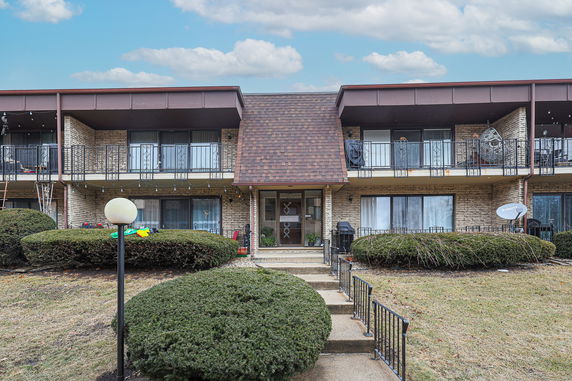 Front view of a two-story residential building with balconies and a central entrance.