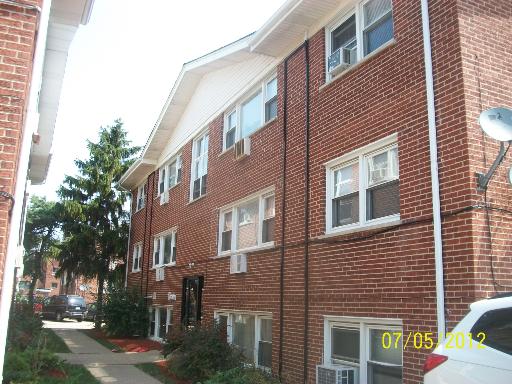 Front view of a three-story brick building with multiple windows.