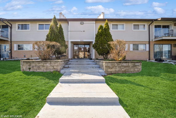 Front view of a two-story residential building with steps leading to the entrance.