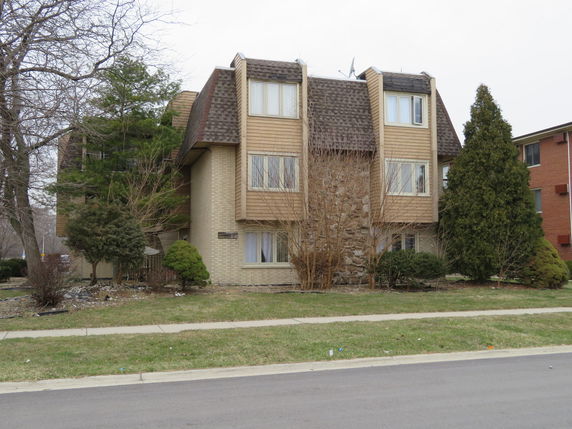 Front view of a multi-story building with a brick and wood exterior.