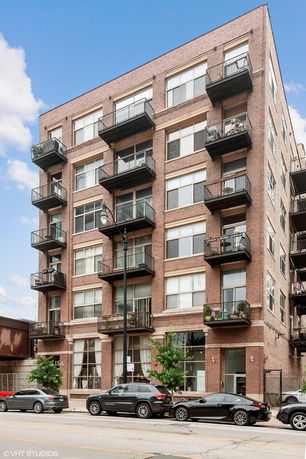 Front view of a multi-story brick apartment building with balconies.