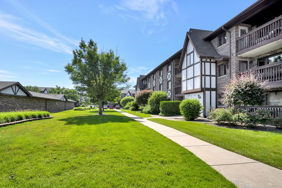 Front view of a multi-story residential building with balconies and a walkway.