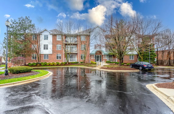 Front view of a three-story brick apartment building with balconies.