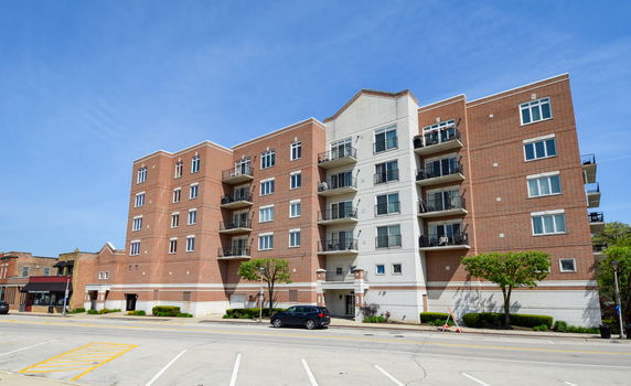 Front view of a multi-story brick apartment building with balconies.
