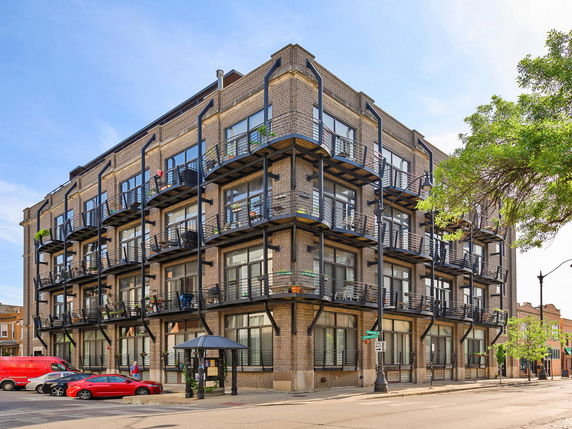Front view of a four-story apartment building with balconies on each level.