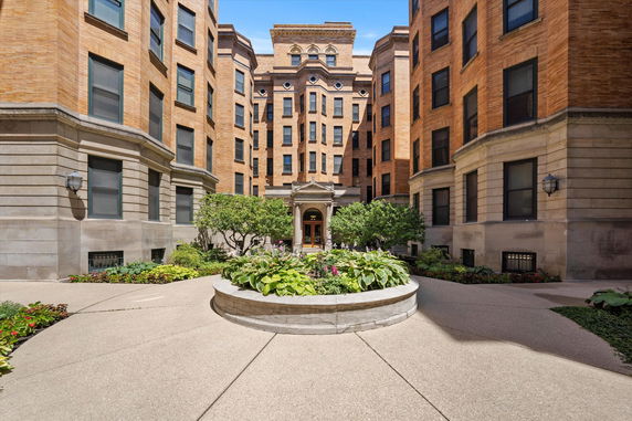 Front view of a multi-story brick building with symmetrical design and a landscaped entrance.