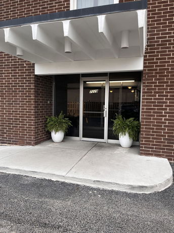 Front view of a brick building with a glass entrance and a small awning.