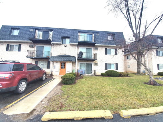 Front view of a multi-story residential building with balconies and a central entrance.