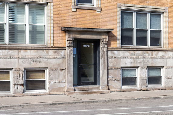 Front view of a multi-story brick building with large windows and a glass front door.