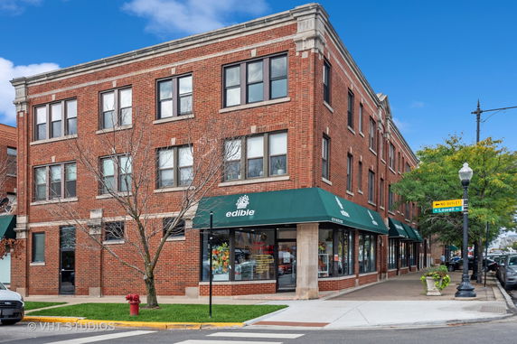 Front view of a multi-story brick building with commercial space on the ground floor.