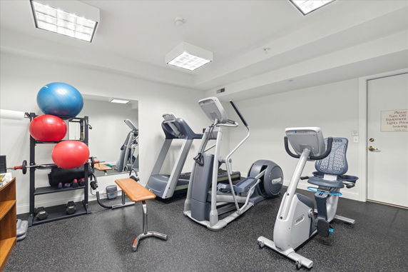Indoor room equipped with exercise machines, exercise balls, and gym equipment.