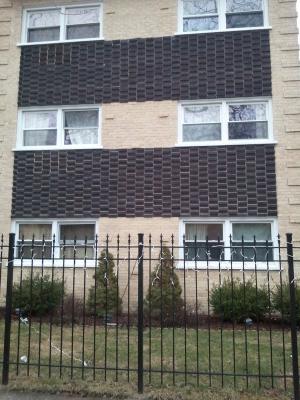 Front view of a multi-story building with distinctive brick pattern and black fence.