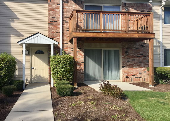 Front view of a building with a wooden balcony and a small porch entrance.