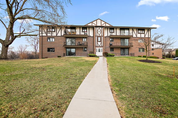 Front view of a multi-story apartment building with brick exterior and balconies.