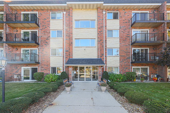 Front view of a multi-story brick apartment building with balconies.