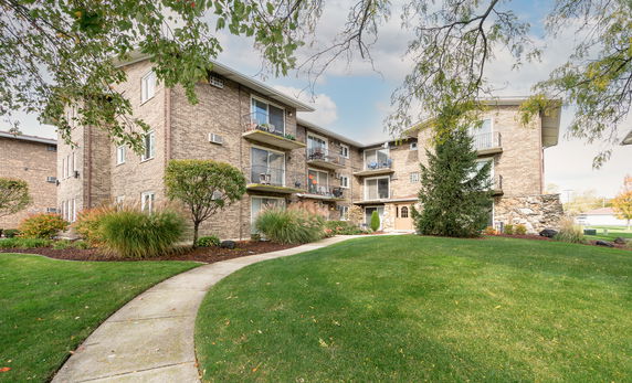 Front view of a multi-story brick apartment building with balconies.