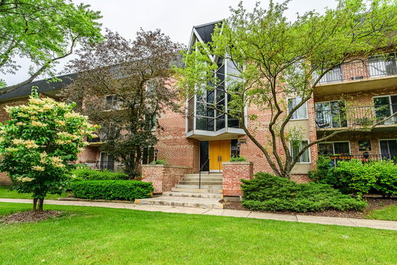 Front view of a two-story building with a red brick facade and a glass entrance.