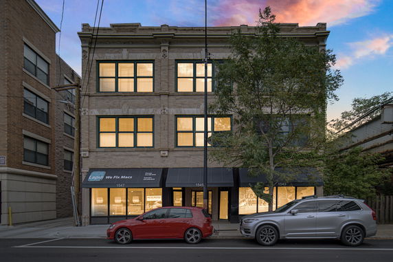 Front view of a multi-story commercial building with a brick facade and large windows.
