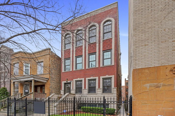 Front view of a three-story brick house with arched windows on the top floor.