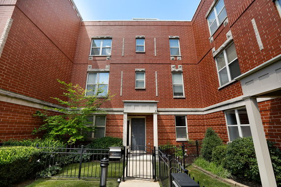 Front view of a multi-story brick building with a gated entrance.