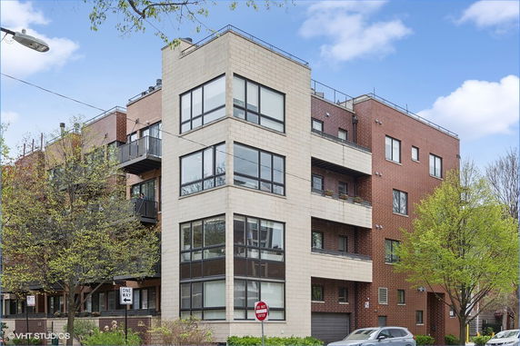 Front view of a multi-story apartment building with large windows and balconies.
