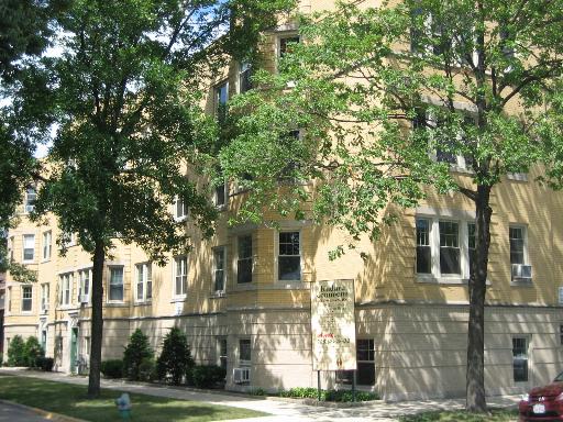 Front view of a multi-story apartment building with beige exterior and multiple windows.