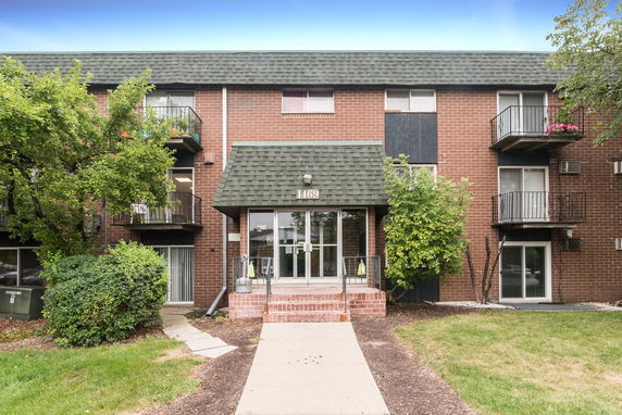 Front view of a three-story apartment building with brick exterior and balconies.