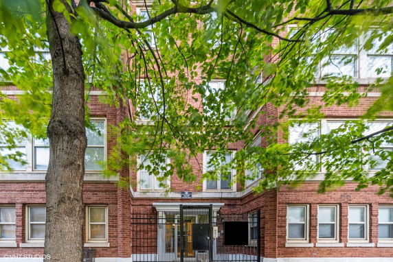 Front view of a multi-story brick building with windows and a gated entrance.