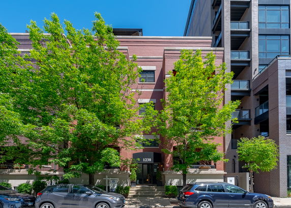 Front view of a multi-story brick building with a central entrance and large windows.