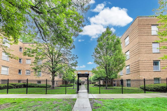 Front view of a multi-story brick apartment building with gated entrance.