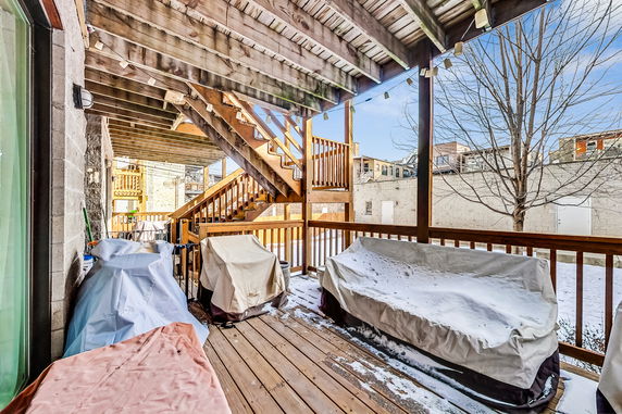 View from an outdoor covered patio with wooden railings and stairs leading to the upper level.