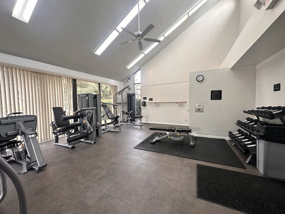 Interior view of a gym area with exercise machines and weights.