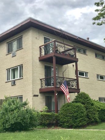 Front view of a three-story building with balconies and an American flag.