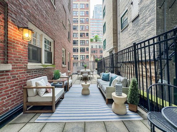 Outdoor space between two buildings with seating area on a tiled patio.