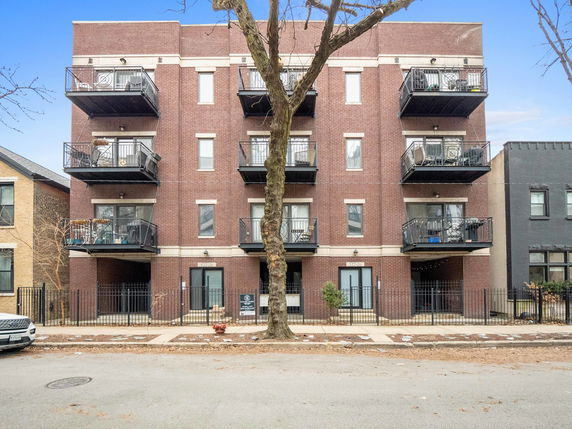 Front view of a multi-story residential building with brick facade and balconies.