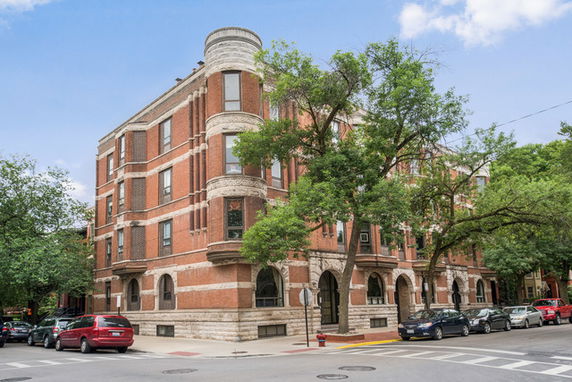 Front view of a multi-story brick building with rounded corner features.