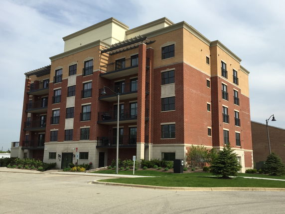 Front view of a multi-story brick apartment building with balconies.