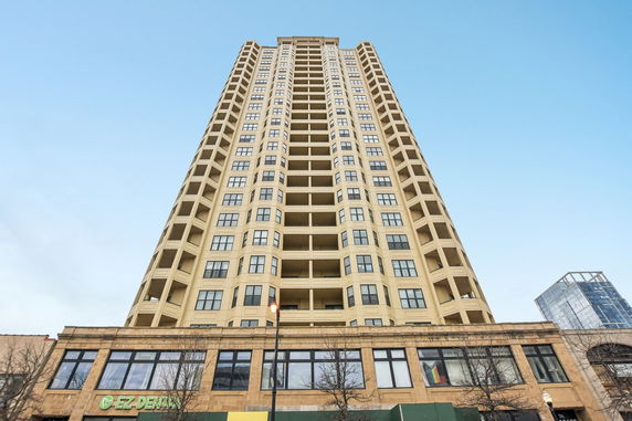 Front view of a high-rise building with multiple balconies and a commercial space on the ground floor.