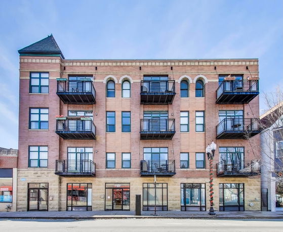 Front view of a four-story brick apartment building with multiple balconies.