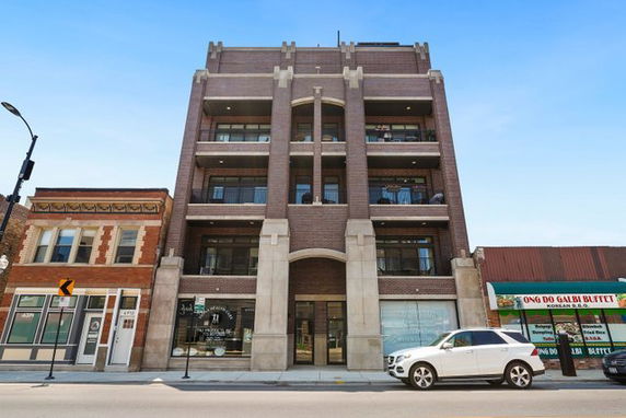 Front view of a multi-story brick building with balconies and large entrance.