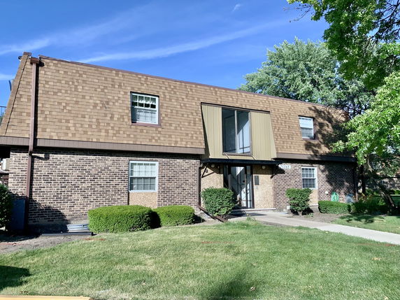 Front view of a two-story house with a sloped roof and brick facade.
