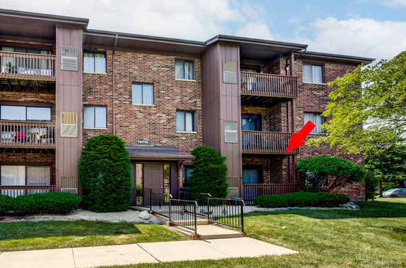 Front view of a multi-story brick apartment building with balconies.