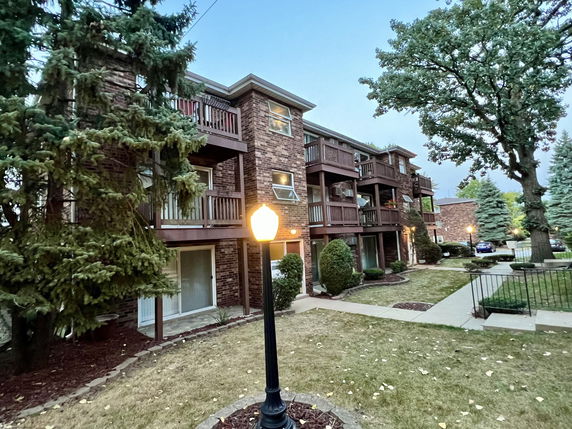 Front view of a three-story brick apartment building with balconies.
