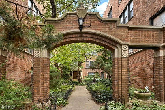Front view of a brick building with an arched entrance and garden path.