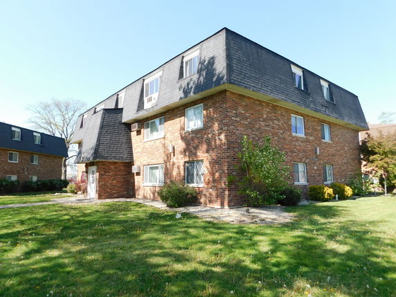 Front view of a three-story brick apartment building with a mansard roof.