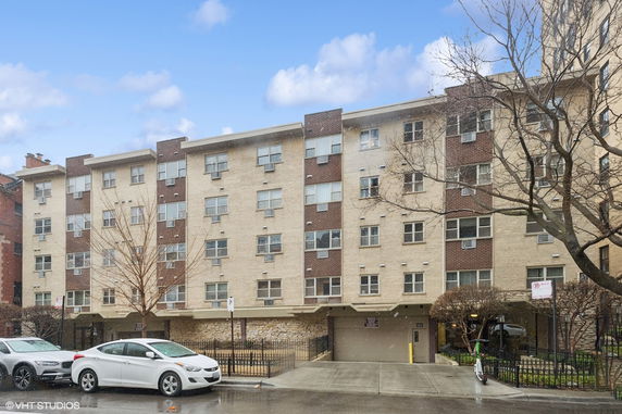 Front view of a multi-story apartment building with a flat roof and various windows.