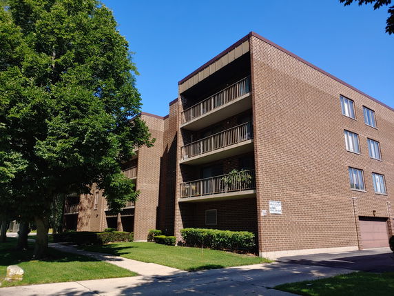 Front view of a multi-story apartment building with brick exterior and balconies.