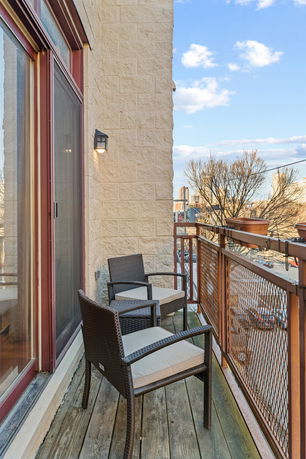 Balcony view showing outdoor chairs and railing with a cityscape in the background.