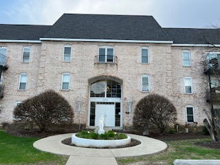 Front view of a brick three-story apartment building with a central entrance and small balconies.