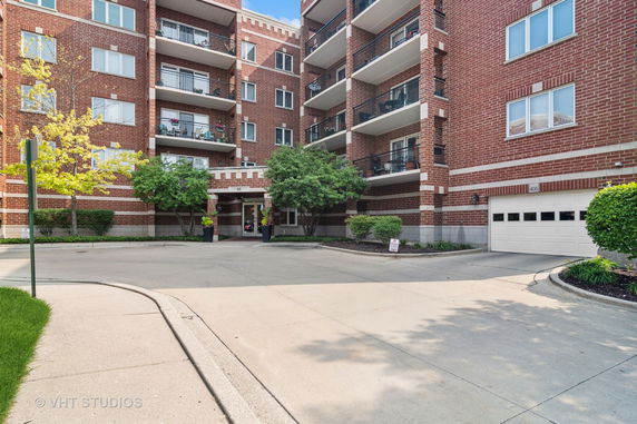 Front view of a multi-story brick apartment building with balconies.